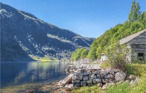 an old cabin next to a lake with mountains at 3 Bedroom Lovely Home In Vikanes in Eikemo +24 photos