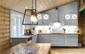 a kitchen with white cabinets and a wooden table at 3 Bedroom Lovely Home In Vikanes in Eikemo