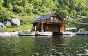 a house on the water next to two boats at Amazing Home In Farsund With Wifi in Farsund