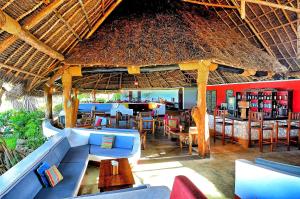 a restaurant with tables and chairs and a straw roof at Pongwe Beach Hotel in Pongwe