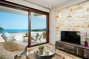 a living room with a tv and a stone wall at Agorastos Hotel in Koinyra