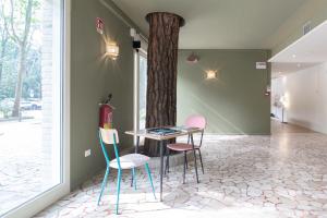 a table and chairs in a room with a tree at Hotel Millepini in Marina Romea