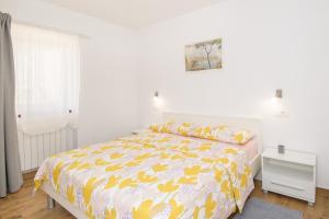 sypialnia z łóżkiem z żółto-białą narzutą w obiekcie Apartment Bruneta 2 with Terrace w mieście Vabriga
