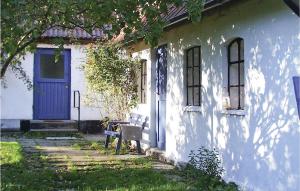 una casa blanca con una puerta azul y un banco en Gorgeous Home In Skillinge With Sauna, en Skillinge
