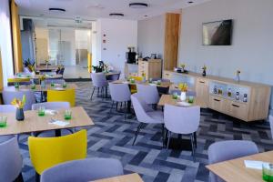 um restaurante com mesas de madeira e cadeiras amarelas em KIRÁLY PARK HOTEL em Szombathely