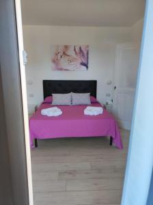 a bedroom with a pink bed with two towels on it at Villa Ada in Santa Domenica