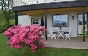 una casa con flores rosas en una terraza de madera en Beautiful Apartment In Norheimsund With House Sea View, en Norheimsund
