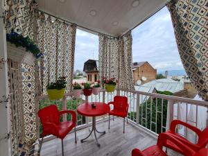 einen Balkon mit roten Stühlen, einem Tisch und einem Fenster in der Unterkunft Lowell Hotel in Tbilisi City