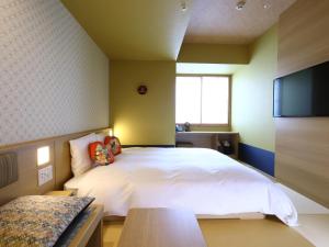a bedroom with a white bed and a flat screen tv at Onyado Nono Osaka Yodoyabashi in Osaka