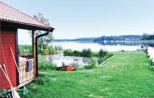 a house with a grassy yard next to a lake at Amazing Home In Strängnäs With Sauna in Aspö
