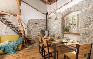 ein Esszimmer mit einem Tisch, Stühlen und einer Steinmauer in der Unterkunft Amazing Home In Mucici With Kitchen in Mučići