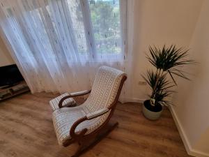 a white rocking chair in a room with a potted plant at Golden Fields Apartment near the Old Town in Kotor