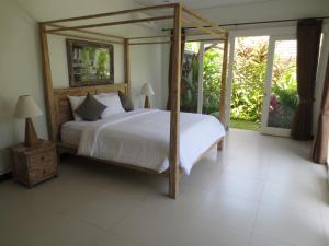 乌布珠玛酒店的一间卧室配有一张带木制天篷的大床 更多35张照片