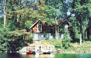 a house sitting on the side of a lake at Stunning Home In Ljungsarp With 4 Bedrooms, Sauna And Wifi in Ljungsarp