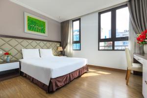 um quarto de hotel com uma cama, uma secretária e janelas em Yolo Wa Hotel em Hanói