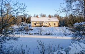 a house in the snow with a pond in front at Cozy Home In Marieholms Bruk With Kitchen in Marieholm