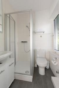 a white bathroom with a shower and a toilet at Aparthotel Stoll in Bad Soden am Taunus