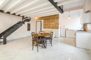 uma cozinha e sala de jantar com uma mesa de madeira e cadeiras em Loft In The Old Town em Alghero