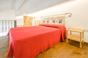 um quarto com uma cama vermelha e uma cadeira em Loft In The Old Town em Alghero