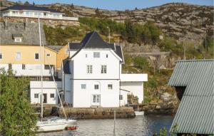 a white house on the water with a boat in it at Beautiful Apartment In Steinsland With 4 Bedrooms And Wifi in Hommelsund