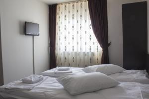 a bed with white sheets and pillows in front of a window at Pensiunea Vidcom in Floreşti