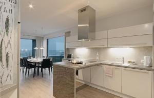 a kitchen with white cabinets and a dining room with a table at Priwallpromenade 1, Whg 3 in Travemünde