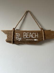 un cartel de madera que dice a la playa en Calm sea guesthouse en Weymouth