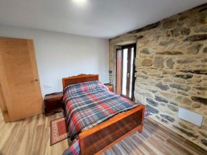 ein Schlafzimmer mit einem Bett und einer Steinmauer in der Unterkunft Casa Paris grande en Costa da Morte, Dumbria in Dumbría