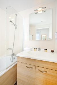 La salle de bains est pourvue d'un lavabo blanc et d'une douche. dans l'établissement Residhome Clermont Ferrand Gergovia, à Clermont-Ferrand