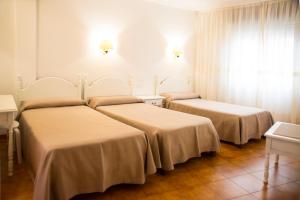 two beds in a room with white walls at Hotel Cachalote in Portonovo