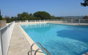 ein großer blauer Pool mit einem weißen Zaun in der Unterkunft Studio de vacances dans résidence avec piscine in Cogolin