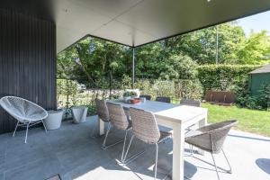una mesa blanca y sillas en un patio con sombrilla en B&B Eat&Sleep, en Evergem