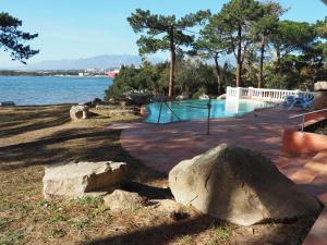 a swimming pool with rocks next to the water at Villa PINEDE in Porto-Vecchio
