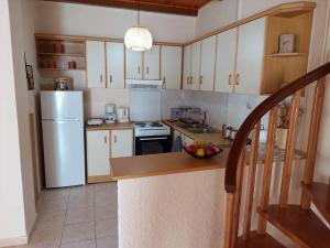 una cocina con electrodomésticos blancos y un bol de fruta en una barra en Anna's House en Anavyssos