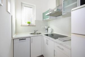 kuchnia z białymi szafkami, umywalką i oknem w obiekcie Apartment Kosic n2 beautiful & cosy w Krku