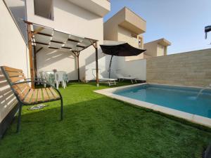 einen Hinterhof mit Pool und Sonnenschirm in der Unterkunft L’isola di Cristiano Marzamemi in Marzamemi