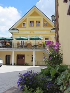 a yellow building with tables and umbrellas at Wellness Hotel TTC in Vrchlabí