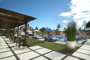 a resort with a swimming pool and a resort with chairs at Villa Mahapala in Sanur