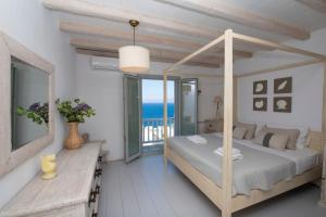 Villa Amarone في مدينة ميكونوس: غرفة نوم مع سرير مظلة مع إطلالة على المحيط +43 صورة