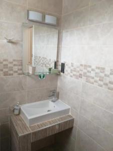 een badkamer met een witte wastafel en een spiegel bij Panoramic Holidays - Deluxe 4 in Peyia