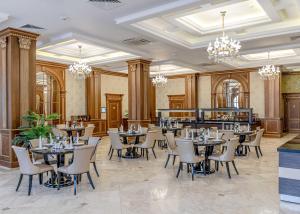 ein Esszimmer mit Tischen, Stühlen und Kronleuchtern in der Unterkunft Sultan Palace Hotel in Atyrau