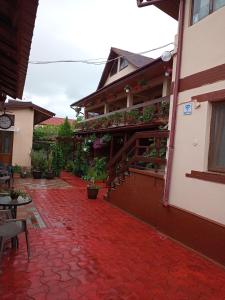 a building with a red carpeted walkway next to a house at Casa Ecaterina 2 Mai in 2 Mai