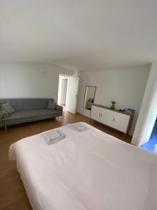 Cama blanca grande en habitación con sofá en Apartman S&D Rogoznica, en Rogoznica
