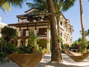 a building with palm trees and two hammocks in front of it at Residencia Boracay in Boracay