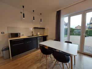kuchnia ze stołem i krzesłami oraz duże okno w obiekcie Avilla Apartamenty w Łebie