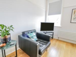a living room with a leather couch and a tv at 18 Tyn Celyn in Llandudno