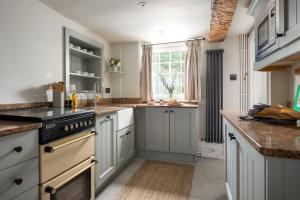a kitchen with white cabinets and a window at Mulberry, A Luxury Two Bed Cottage in Painswick in Painswick