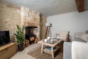 a living room with a stone wall and a fireplace at Mulberry, A Luxury Two Bed Cottage in Painswick in Painswick
