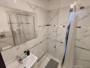 a white bathroom with a sink and a mirror at Micadas Apartamenty in Piaseczno