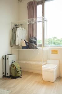 una stanza con una valigia e uno scaffale con vestiti di Corner Hostel & Cafe a Taipei
